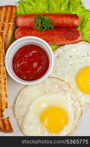 Fried eggs with sausages, toasts, greens and sauce