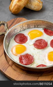 fried eggs with turkish sausage with bread and tea on dark stone table