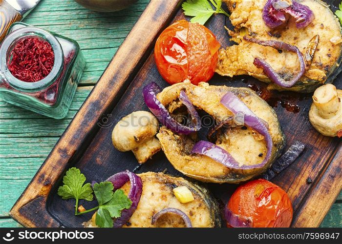 Fried fish,mackerel with grilled vegetables on wooden kitchen board. Fried mackerel with vegetables