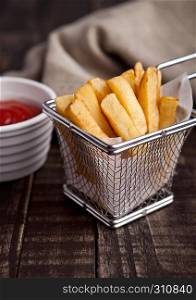 Fried french fries chips in fryer with ketchup on wood. with fresh potatoes and kitchen towel