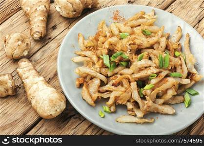 Fried Jerusalem artichoke roots or french fries on retro wooden background.Sweet potato fries. Fried Jerusalem artichoke on plate