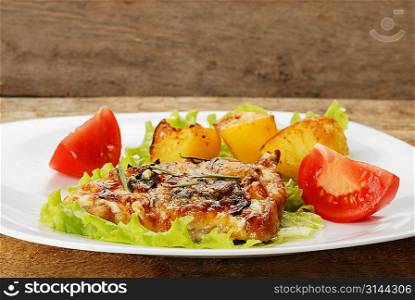 fried meat, baked potatoes and slices of tomato