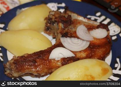 Fried meat on the bone with a fresh onion and boiled potatoes on the plate