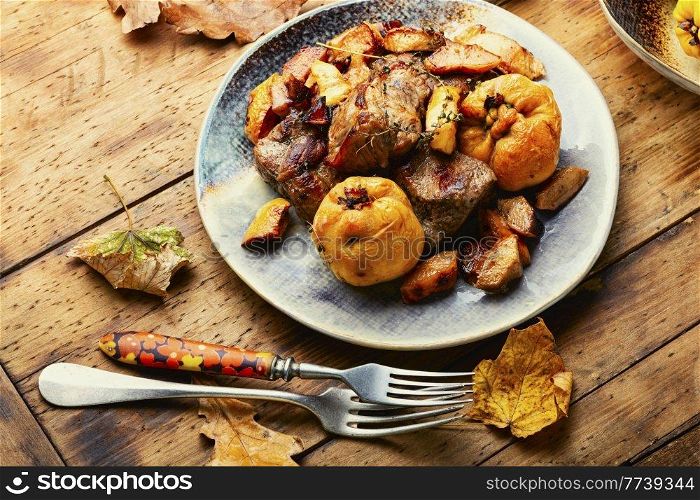 Fried meat with autumn quince on the plate. Stewed pieces of meat with quince
