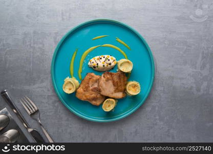 fried meat with greens in a plate on a gray background. the food, the view from the top