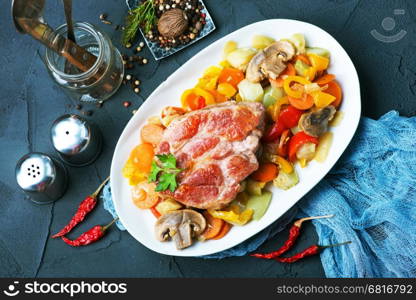 fried meat with vegetables on plate and on a table