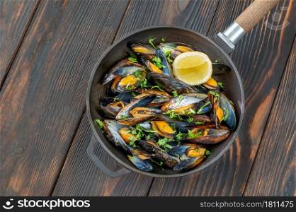 Fried mussels with lemon and fresh parsley on the frying pan
