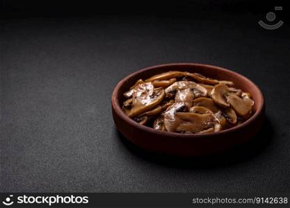 Fried or stewed ch&ignonμshrooms in the form of slices with onions on a brown ceramic plate on a dark concrete background