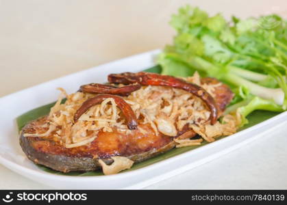 Fried pickled fish , onion and chili served with fresh vegetable on dish