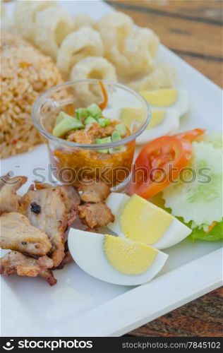 fried pork and boiled egg on white dish served with chili sauce and fresh vegetable