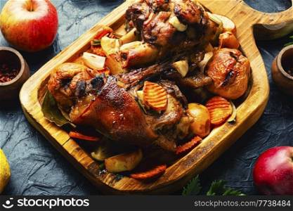 Fried pork knuckle with apples on cutting board. Meat grilled with apples and quince