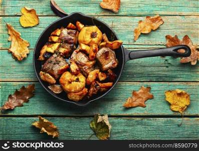 Fried pork meat with autumn quince in iron cast pan.Stewed meat. Baked meat cuts with quince