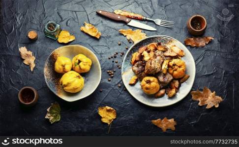 Fried pork meat with autumn quince on the plate. Baked pieces of meat with quince