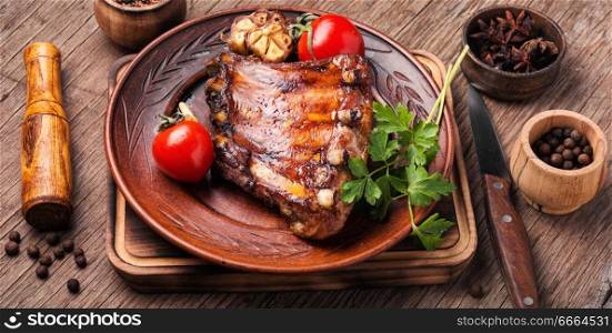 Fried pork ribs with tomato on wooden table. Tasty roasted ribs