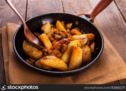 Fried potato and champignons in the cast-iron frying pan