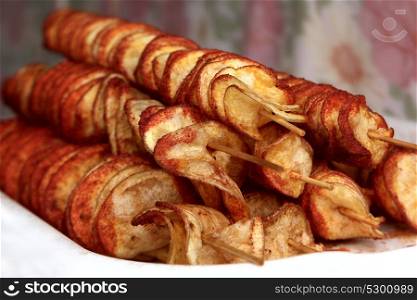 Fried potato chips on wooden skewers close-up
