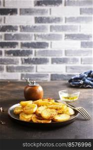 Fried potato wedges with oil, herbs on stone board