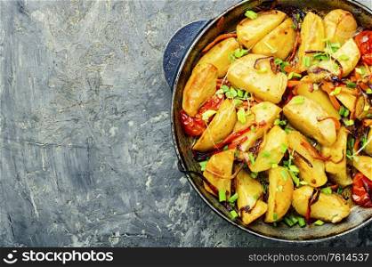 Fried potato with tomato, onion and carrot.Copy space. Potatoes fried in pan