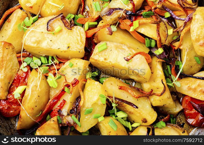 Fried potato with tomato, onion and carrot.Food background. Roasted potato,close up