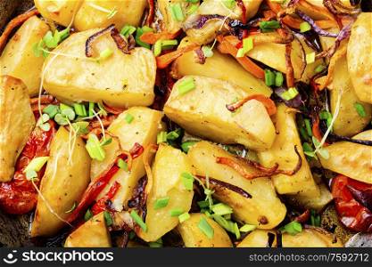 Fried potato with tomato, onion and carrot.Food background. Roasted potato,close up