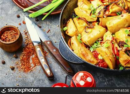 Fried potato with tomato, onion and carrot. Roasted potato in a frying pan