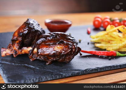 fried potatoes and pork with bone on plate