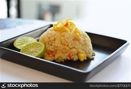 fried rice served with omelet slice and lemon slice