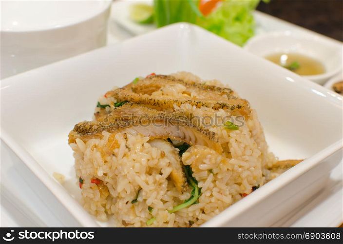 Fried rice with fried fish on dish.