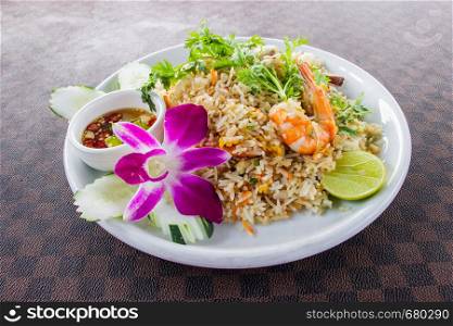 Fried rice with shrimp on the white ceramic dish decorated with orchid and hot spicy dipping sauce put on leather floor the grid pattern. Top view
