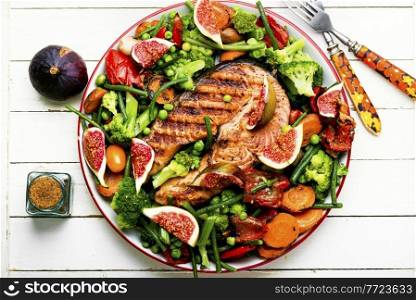Fried salmon steak with figs.Baked trout with vegetable. Trout steak fried with vegetables.