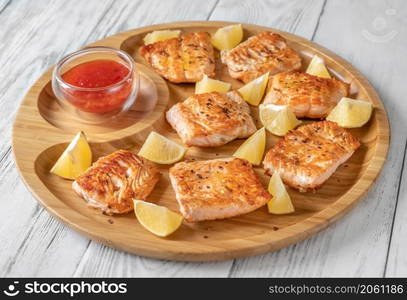 Fried salmon with sauce on the wooden serving tray