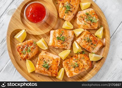 Fried salmon with sauce on the wooden serving tray