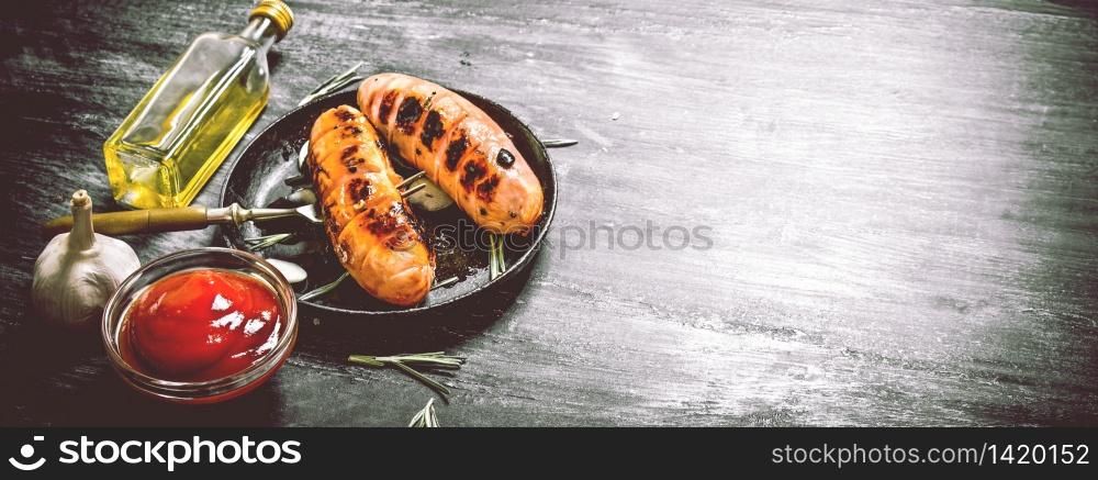 Fried sausages with garlic and tomato sauce in the pan. On the black Board.. Fried sausages with garlic and tomato sauce in the pan.