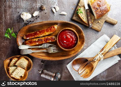 Fried sausages with sauces and herbs on a wooden serving Board. Great beer snack on a dark background. Top view with copy space