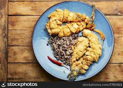 Fried sea bass fish with rice on rice paper. Roasted seafood. Appetizing grilled sea bass fish.