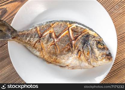 Fried sea bream on the plate: top view