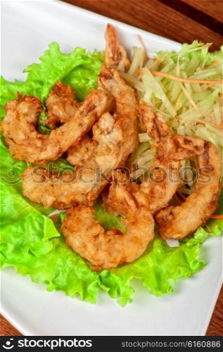Fried shrimps at plate. Fried shrimps with lettuce at white plate