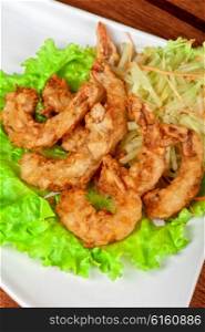 Fried shrimps at plate. Fried shrimps with lettuce at white plate