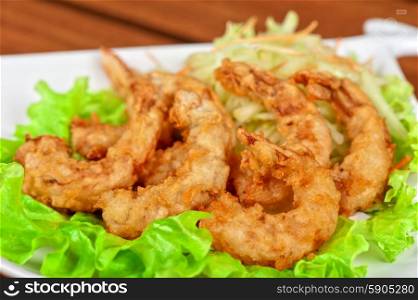 Fried shrimps. Fried shrimps with lettuce at white plate