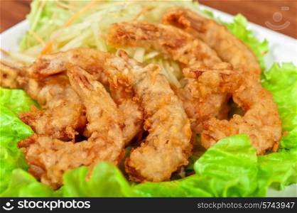 Fried shrimps with lettuce at white plate