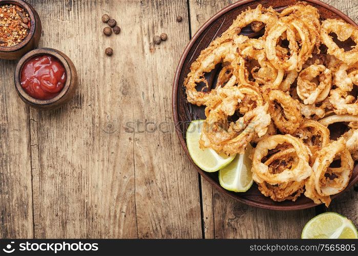 Fried squid rings breaded with lime on wooden background. Crispy fried squid rings