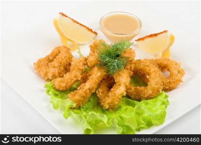 fried squid with salad leaves, sauce, green and lemon on a white background