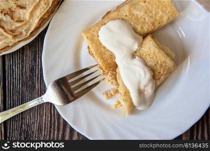 Fried tasty pancakes . Fried pancakes with sour cream on old wooden table