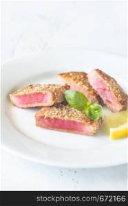 Fried tuna in sesame seeds garnished with fresh basil and slice of lemon