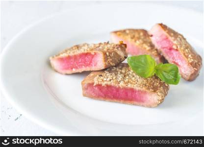 Fried tuna in sesame seeds on the white plate: cross section