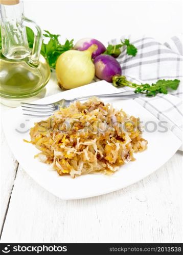 Fried turnips with onions in a plate, oil in decanter, a napkin on white wooden board background