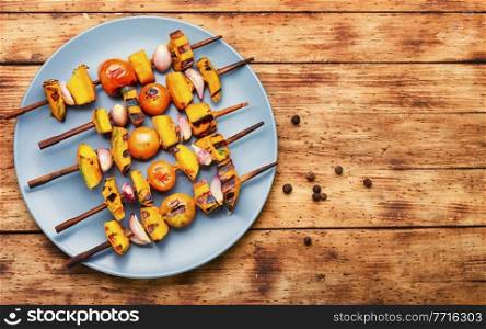 Fried vegetables on skewers, vegetarian skewer kebab. Pumpkin, tomato, zucchini and pepper shashlik.Space for text. Summer vegetable kebab,top view