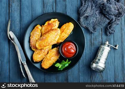 fried wings with tomato on black plate