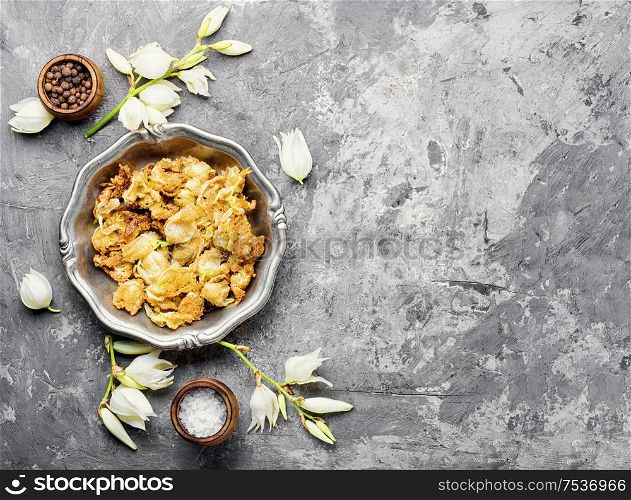 Fried yucca flowers on plate.An unusual dish of edible flowers.Space for text. Fried yucca flowers