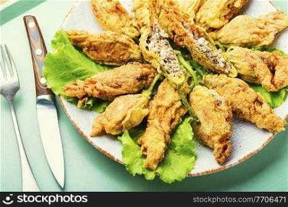 Fried zucchini flowers stuffed with cheese and herbs.Roasted courgette flowers. Stuffed fried zucchini flowers.